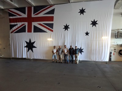 A few of the crew pose in front of the White Ensign